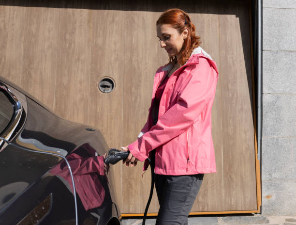 istock Woman Charging Electric Car in Driveway 2153203049