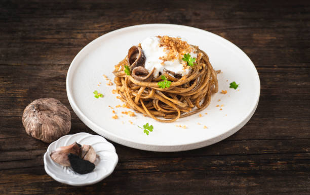 istock Black fermented garlic linguine pasta with  fermented garlic sauce and dry grated bread. A simple recipe in 10 minutes. Modern recipes for Italian pasta, gourmet soft taste. Rustic style, front view 2153204064