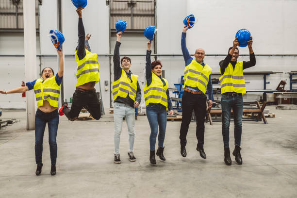 istock Engineers Celebrating with Jump and Hard Hat Toss in Factory 2153204865