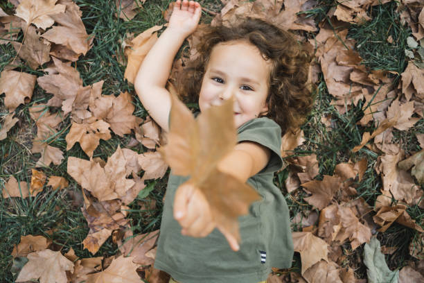 Happy child playing and showing dry leaf of tree