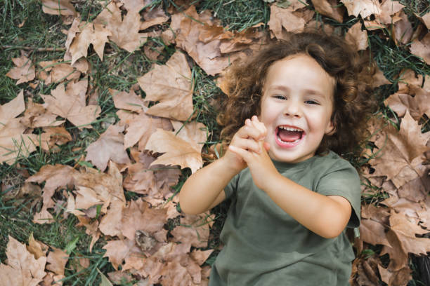 istock Happy child lying playing on the grass with dry leaves 2153206633