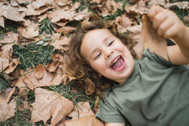 istock Happy child lying playing on the grass with dry leaves, closeup 2153206638