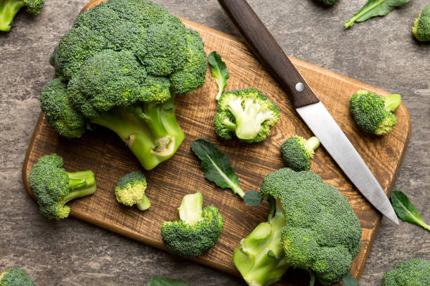 istock fresh green broccoli on wooden cutting board with knife. Broccoli cabbage leaves. light background. Flat lay 2153207794