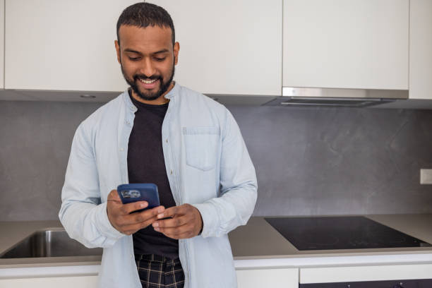 istock Connected Cooking: Young Man Uses Mobile Phone in the Kitchen 2153208590