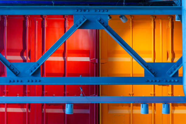View of warehouse building with various colorful rafters (roof beams) and shipping containers