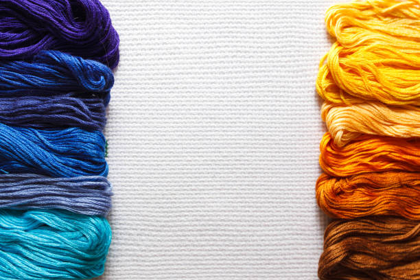 istock Threads of different shades of orange and blue on white fabric. 2153213035