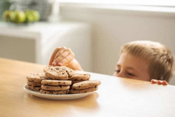 istock A boy is peeping at an appetizing stack of freshly baked chocolate cookies on the table. 2153215234