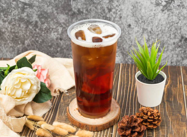 iced Assam black tea with ice cube served in disposable glass isolated n table side view of taiwanese drink