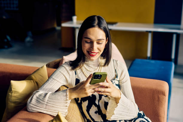 istock Confident Transgender woman relaxed in an office setting, using a mobile phone. Digital communication and social media concept. 2153221655
