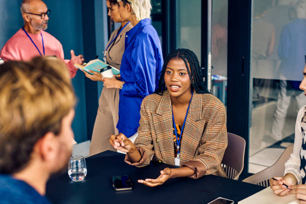 istock Gen Z co-worker discussing strategies with a colleague during a creative meeting. Multitasking and team collaboration in a diverse office environment concept. 2153221960