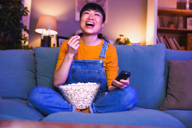 istock Woman switching channels using remote control while watching TV at home late at night 2153223542