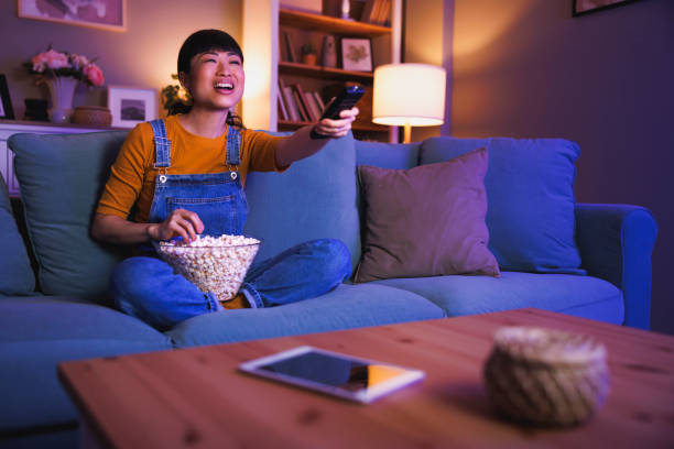 istock Woman turning on TV using remote control relaxing at home late at night 2153223635