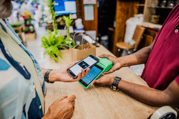 istock Close-up of a customer paying with smartphone using NFC at flower shop 2153229714