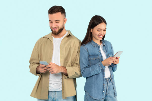 istock Young man and woman using smartphones on blue background 2153233175