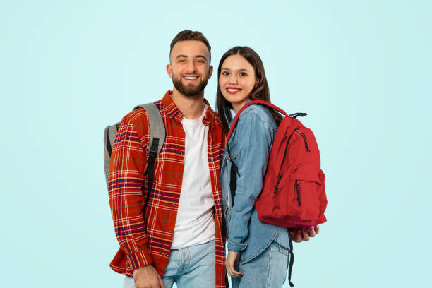 istock Young couple standing with backpacks in studio over blue backdrop 2153233209