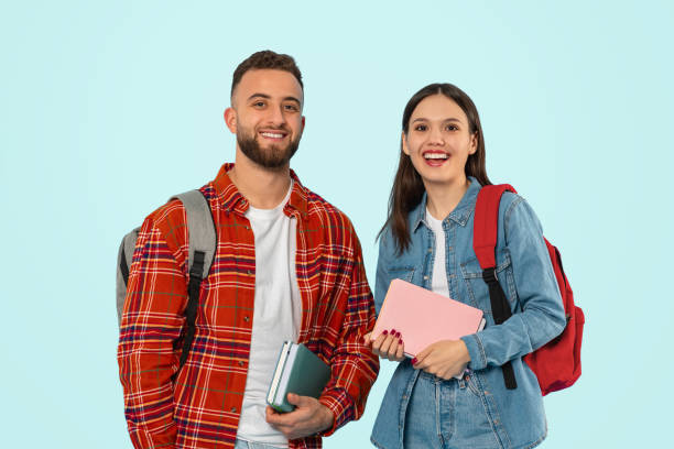 istock Cheerful couple poses casually with backpacks and textbooks in studio 2153233216