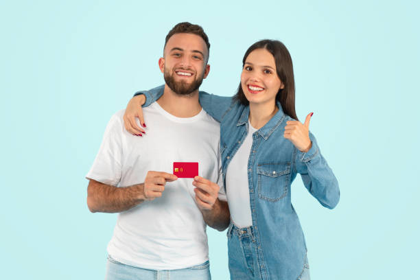 istock couple holding credit card approving offer with thumbs up, studio 2153233255
