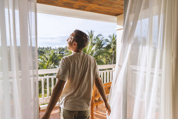 istock Man Embracing Sunlight on Tropical Balcony 2153237209