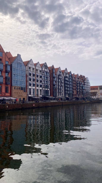 istock Modern waterfront buildings with gabled rooftops reflected in calm water under a cloudy sky, showcasing urban architecture by the river 2153238899