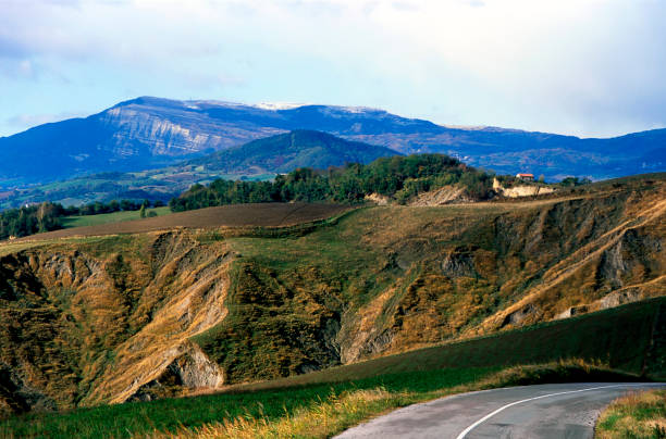 Curving road against eroded fields and a mountain