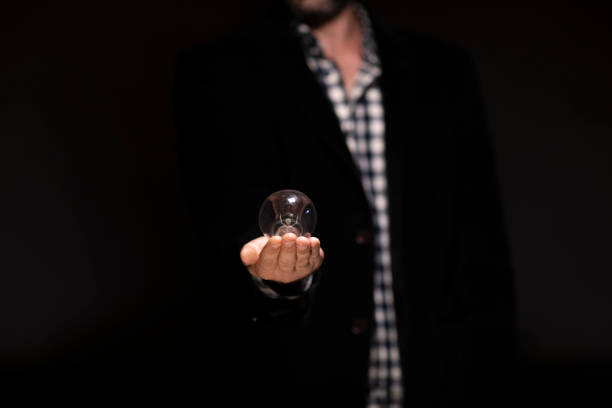 a man holding out with a bulb open hand black background in bulb with idea