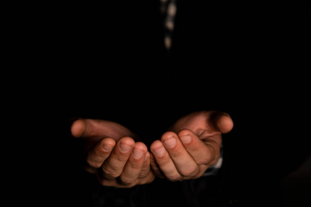 istock a man praying in a dark room, black background, wearing jacket. 2153241738
