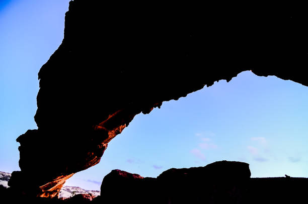 A rock formation with a hole in it and a dark sky in the background