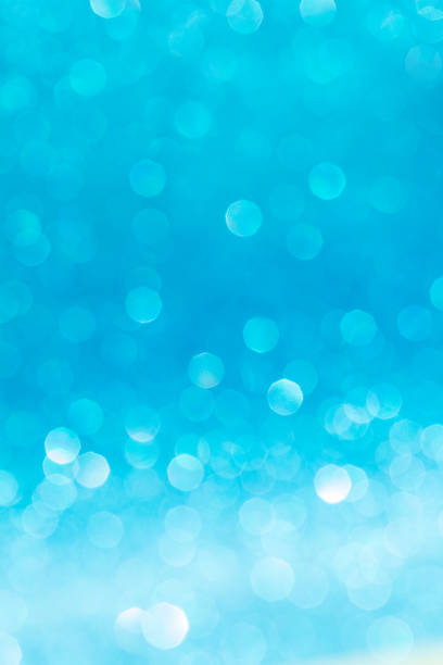 Moving blue shiny lights bokeh, defocused blue background with sparkle. Christmas, New Year, birthday, international women's day, holiday. Vertical. Copy space