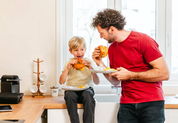 istock Father and son eating hamburger at home 2153252110