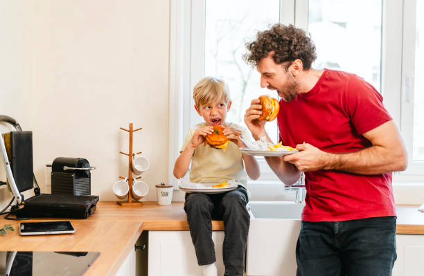 istock Father and son eating hamburger at home 2153252131