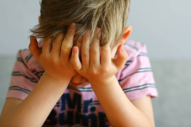 istock the child is tired or sad, covering his face with his hands. 2153252455
