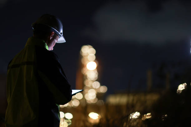 istock Smart  engineer with green safety jacket works on a digital tablet and using a mobile phone at the refinery plant during night shift 2153256918