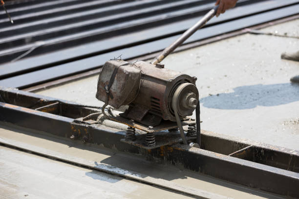 Construction worker operating machine spreading wet concrete pouring at precast concrete wall construction site. Worker or mason working or making smooth surface of concrete with machine at site work