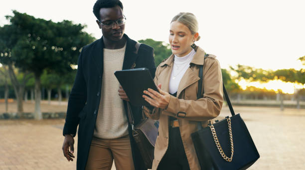 istock Partner, people and walking with tablet outdoor for commuting to work, discussion and online schedule. Happy, coworker and smile with career chat, networking and communication at park in New York 2153263478