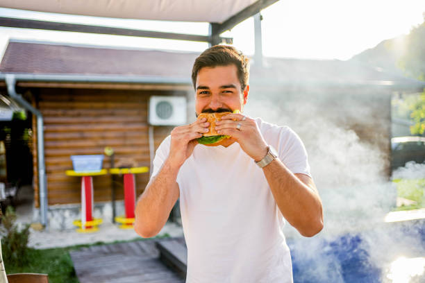 istock Man eating a hamburger at a barbecue party 2153269657