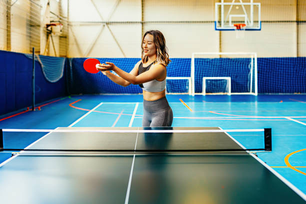 istock A woman holding a red paddle in front of a ping pong table 2153273384