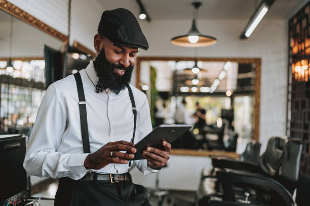 Portrait of a barber holding tablet Portrait of a barber holding tablet black barber stock pictures, royalty-free photos & images
