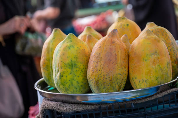A close-up view captures ripe papayas displayed on a tray, enticingly arranged for sale in a bustling bazaar or a vibrant fruit shop