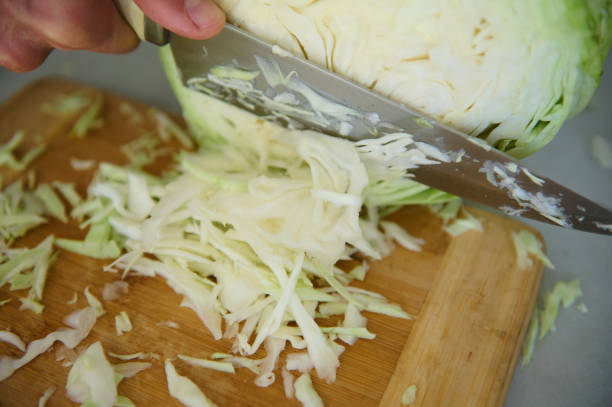istock Close-up chef man using kitchen knife, chopping cutting raw fresh cabbage on a wooden board, preparing raw organic vegan salad 2153278882