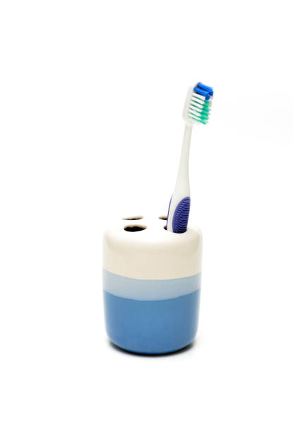 Closeup of a mass produced toothbrush holder with a toothbrush against a white background.