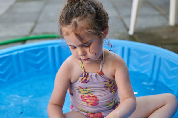 istock pretty little girl playing with water in her blue basin 2153302404