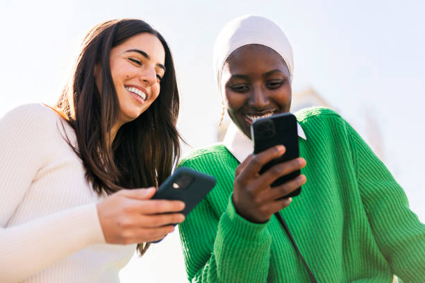 istock two women having fun looking at their mobile phone 2153303375