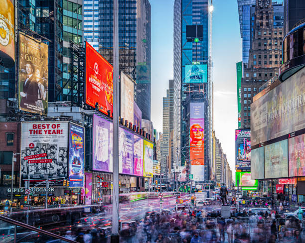 A busy street scene in Times Square in midtown manhattan while tourists and cars crowd the street and sidewalks.