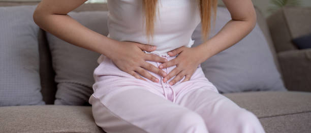 istock Young woman suffering from stomach ache on sofa at home 2153318737