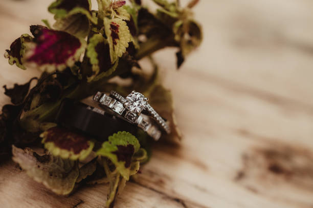 Man and woman's wedding rings with plants on wood background