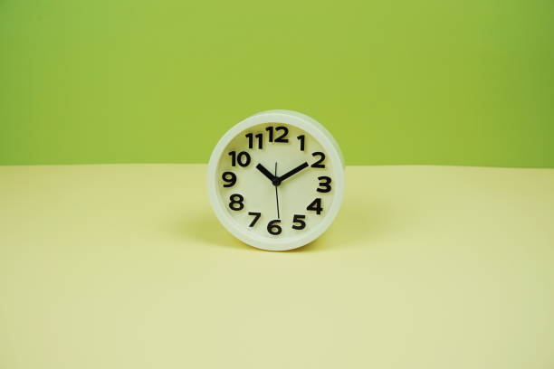 istock White alarm clock with space copy on green and yellow background 2153326425