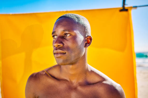 istock New Masculinity: Shirtless man posing on the beach with yellow backdrop. Bright sunny day with blue sky. Masculinity and body positivity concepts. 2153338310