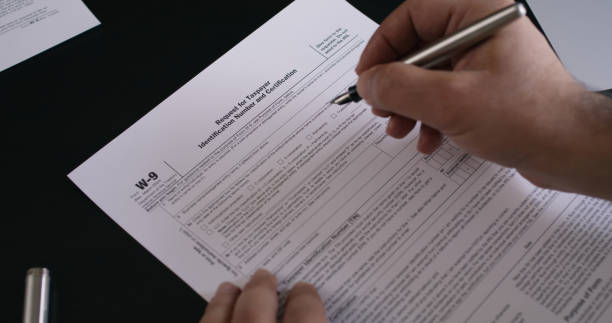 istock Man filling in W-9  Request For Taxpayer Form 2153340316