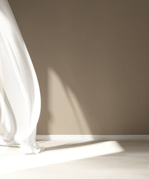 istock Empty room with beige brown wall in sunlight from window with blowing sheer curtain, shadow on wood laminated floor 2153340834