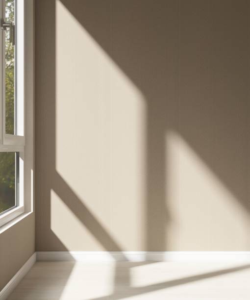istock Empty room with beige brown wallpaper wall in sunlight from window blind, tree shadow on wood laminated floor 2153340839